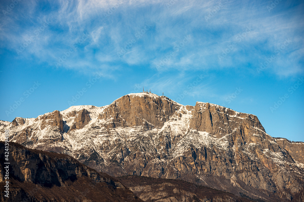 Snowcapped mountain range of the Paganella in winter with the Roda peak (2125 m) with the antennas of the weather station, seen from the Trento city, Adige Valley, Trentino Alto Adige, Italy, Europe. 