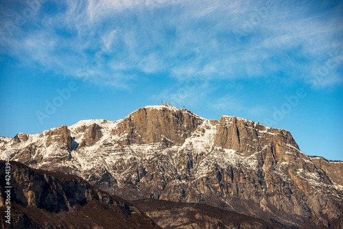 Snowcapped mountain range of the Paganella in winter with the Roda peak (2125 m) with the antennas of the weather station, seen from the Trento city, Adige Valley, Trentino Alto Adige, Italy, Europe. 