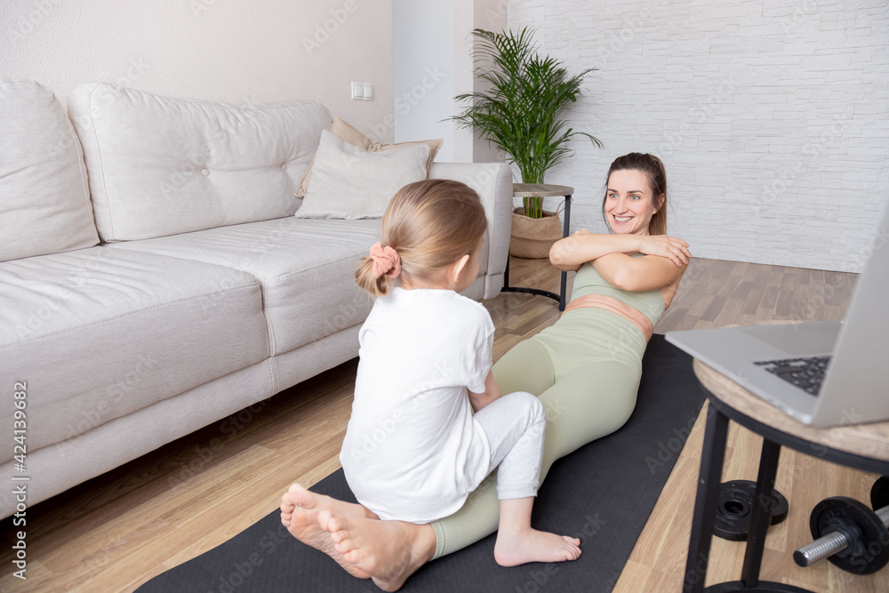 Mother and daughter exercising at home.Healthy and sporty lifestyle. Young beautiful mom in sportswear sporting at home with her little daughter. Useful leisure with a child at home. Mother and daughter exercising at home.Healthy and sporty lifestyle. Young beautiful mom in sportswear sporting at home with her little daughter. Useful leisure with a child at home.