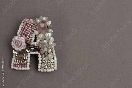 A letter made from beads on grey background