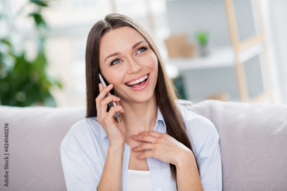 Photo of nice optimistic brunette long hairdo lady sit on coach talk telephone wear blue shirt alone at home
