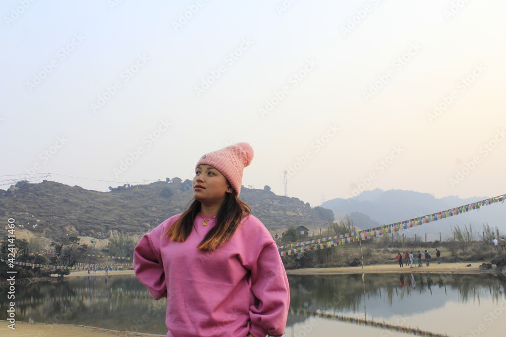 Beautiful Nepali girl is standing in front of lake and putting her hand in waist