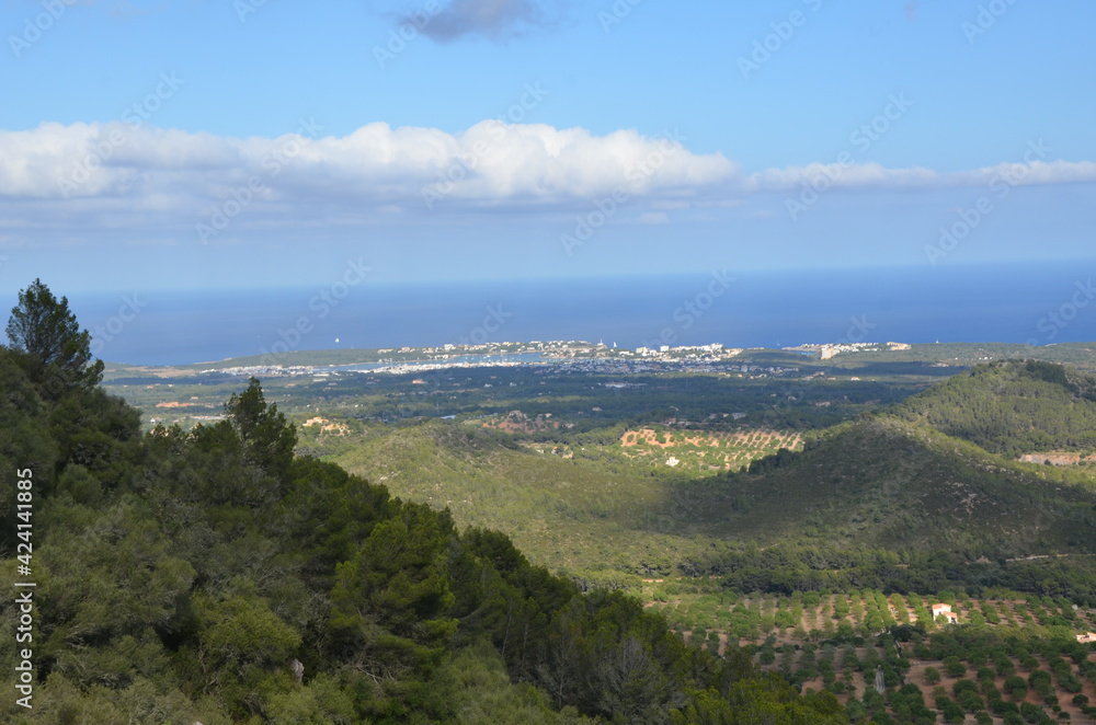 View from the top of the mountain to the beautiful landscape below. View from the mountain to the sea. Green plain in the rays of the summer sun. Mountain walk.