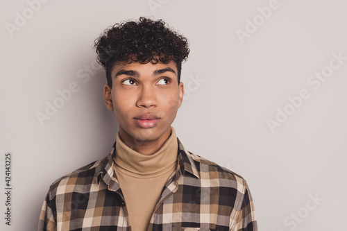 Photo of african guy curious look empty space think wear checkered shirt rollneck isolated grey color background photo