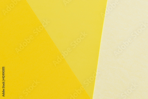 Layout of triangles papers in three different shades of yellow. Light and dark yellow background. Wallpaper in spring colors. Backdrop for writings.