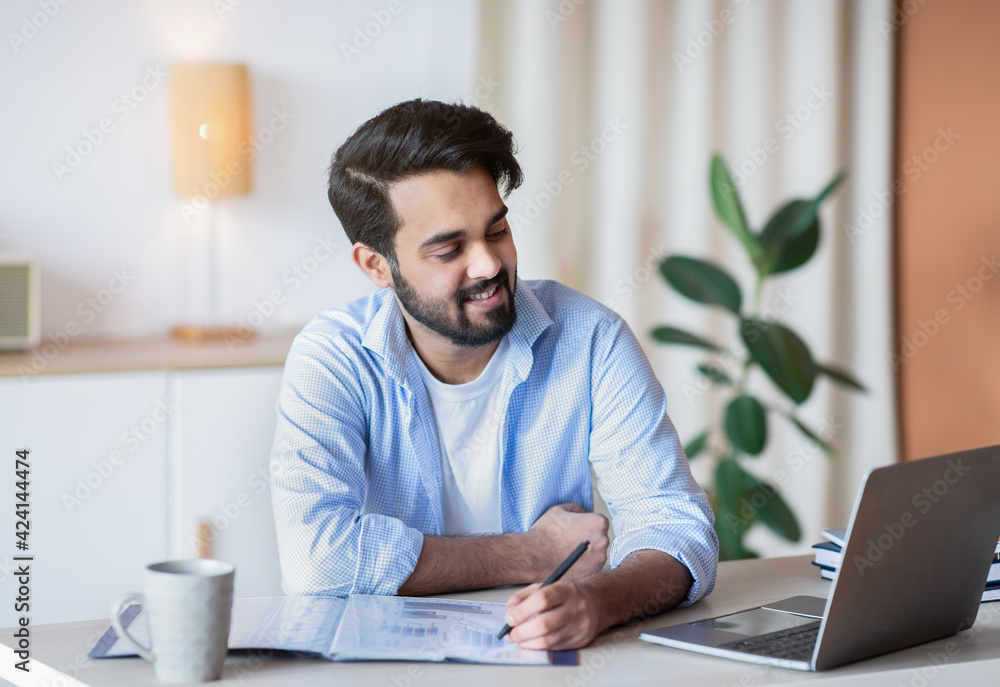Successful Eastern Entrepreneur Working With Documents And Laptop At Home Office Successful Eastern Entrepreneur Working With Documents And Laptop At Home Office