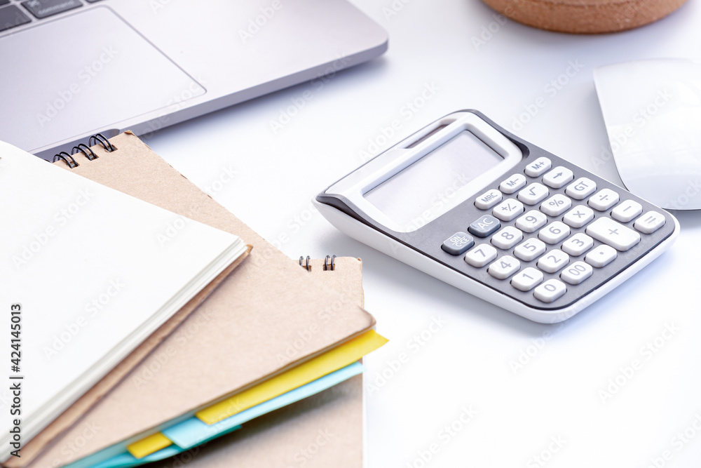 Calculators with a notebook and laptop and a mouse in workspace Calculators with a notebook and laptop and a mouse in workspace