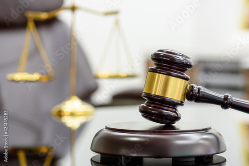 Foto Legal office of lawyers, justice and law concept : Wooden judge gavel or a wood hammer and a soundboard used by a judge person on a desk in a courtroom with a blurred brass scale of justice behind