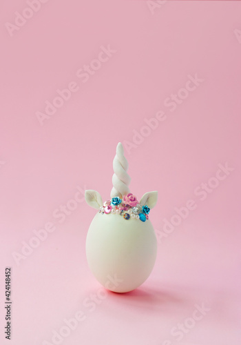 Single white egg, with unicorn decoration; Creative minimal Easter background with copy space