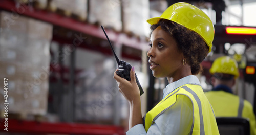 Afro-American female worker of warehouse reporting through walkie-talkie photo