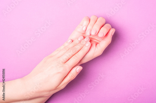 Beautiful female hands showing fresh cute manicure  skin and nail care concept  purple background