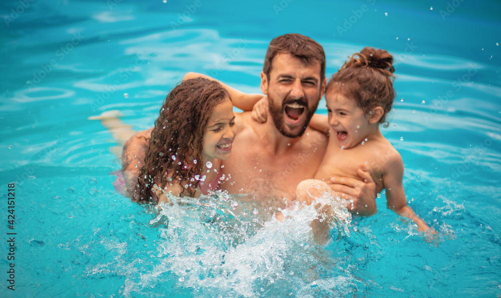 Father with kids playing in the pool.