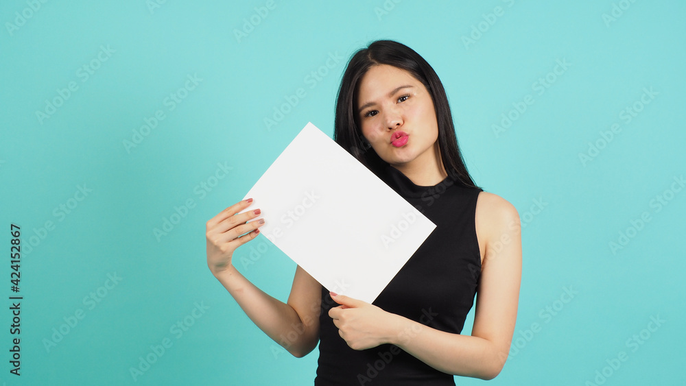 Asian woman is holding blank empty paper board on green or mint or Tiffany Blue background. Asian woman is holding blank empty paper board on green or mint or Tiffany Blue background.