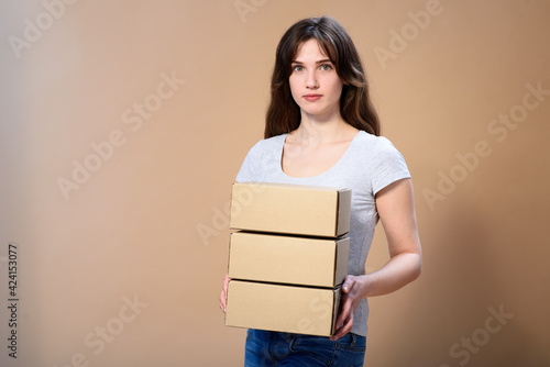 Girl with loose hair and craft boxes on beige background © maxfotoadobe