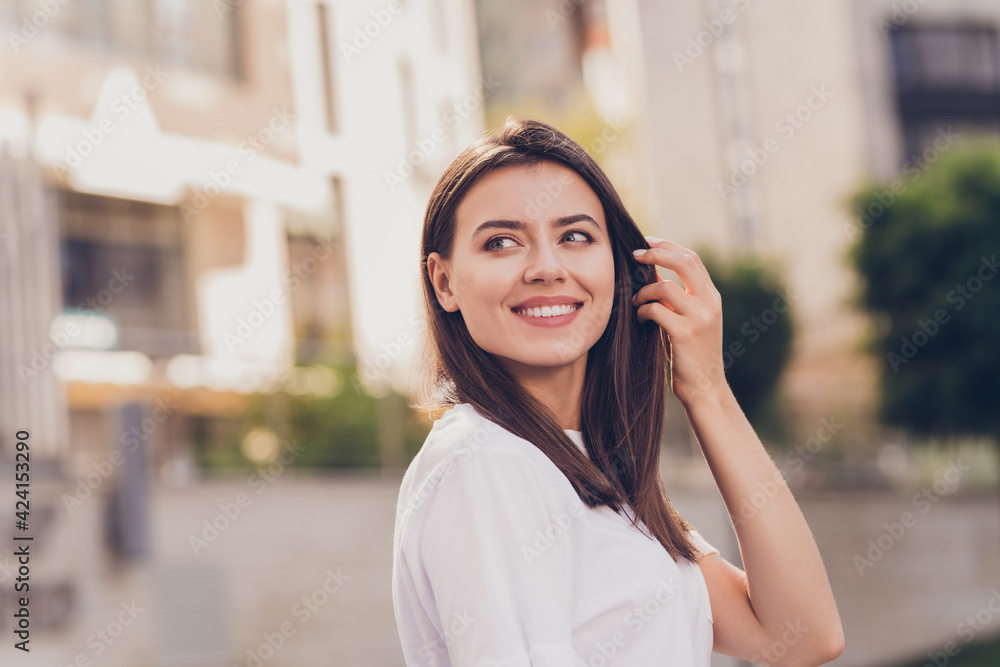 Photo portrait of pretty girl wearing white t-shirt walking on summer streets smiling looking at side Photo portrait of pretty girl wearing white t-shirt walking on summer streets smiling looking at side