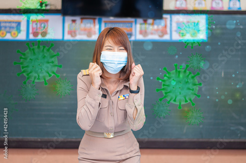 Female thai teacher in uniform standing in front of the classroom wearing mask with green virus around her