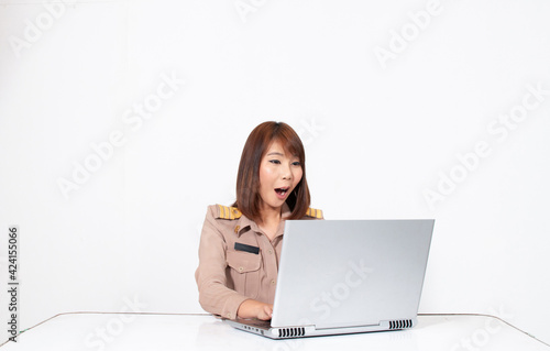 Female thai teacher in uniform sitting with white background using computer