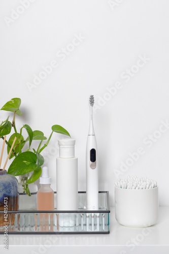 Beauty health care composition with ear sticks in casket, toothbrush, towel, serum on white table. Women's beauty treatment routine concept