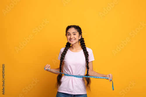 Happy Indian Woman Measuring Waist With Tape. Slimming Concept