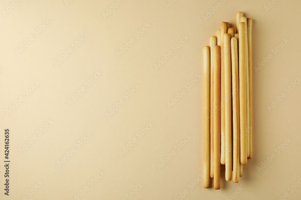 Tasty grissini breadsticks on beige background, space for text Tasty grissini breadsticks on beige background, space for text