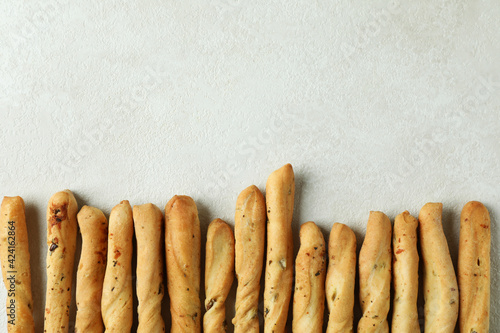 Tasty grissini breadsticks on white textured background
