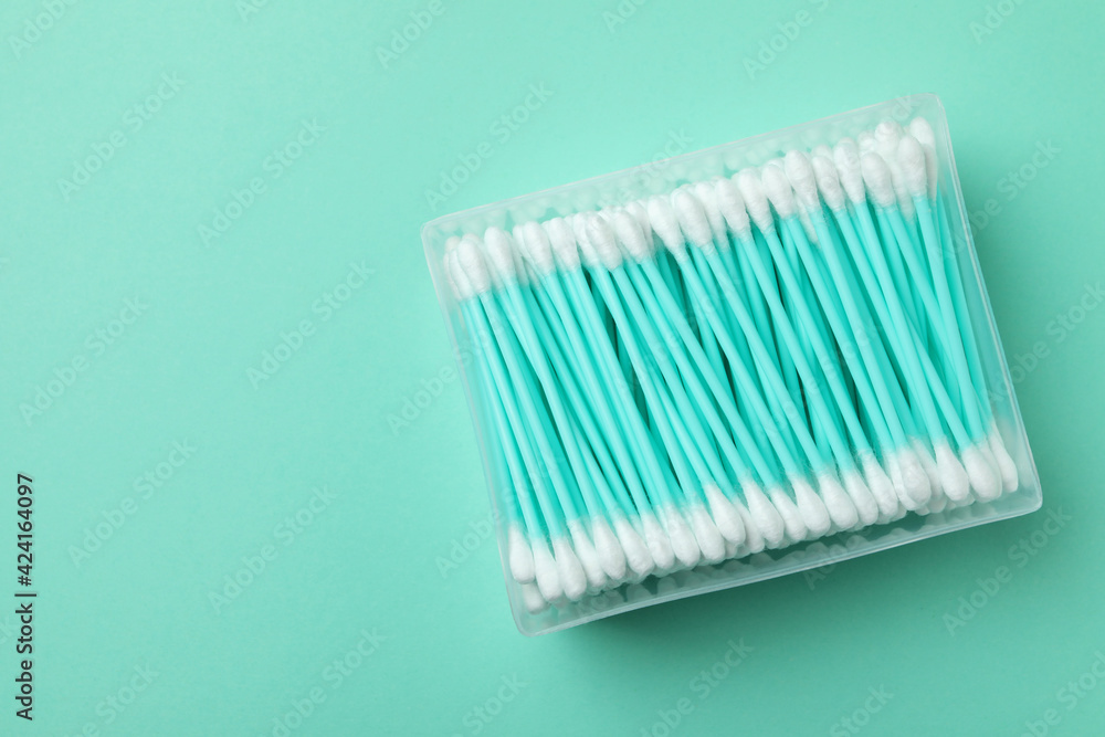 Plastic box with cotton swabs on mint background Plastic box with cotton swabs on mint background