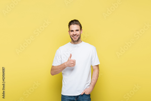 smiling man with hand in pocket showing like on yellow