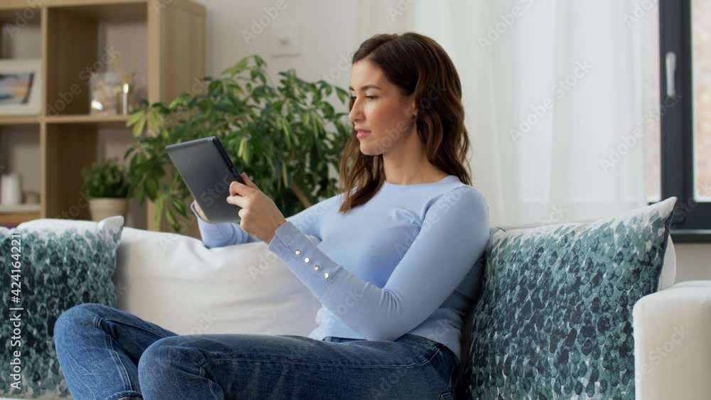 people, technology and leisure concept - happy young woman with tablet pc computer sitting in chair at home people, technology and leisure concept - happy young woman with tablet pc computer sitting in chair at home