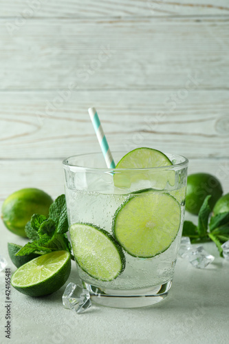 Glass of mojito cocktail and ingredients against wooden background