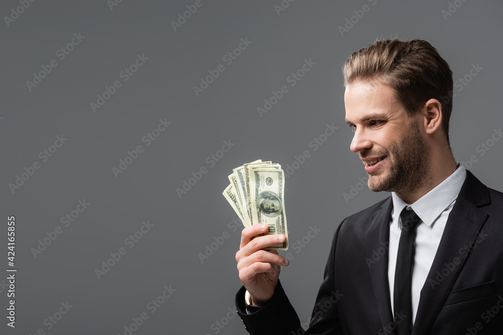 pleased executive manager holding dollars isolated on grey pleased executive manager holding dollars isolated on grey