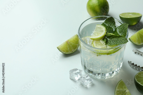 Glass of mojito cocktail and ingredients on white background
