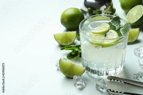 Glass of mojito cocktail and ingredients on white background