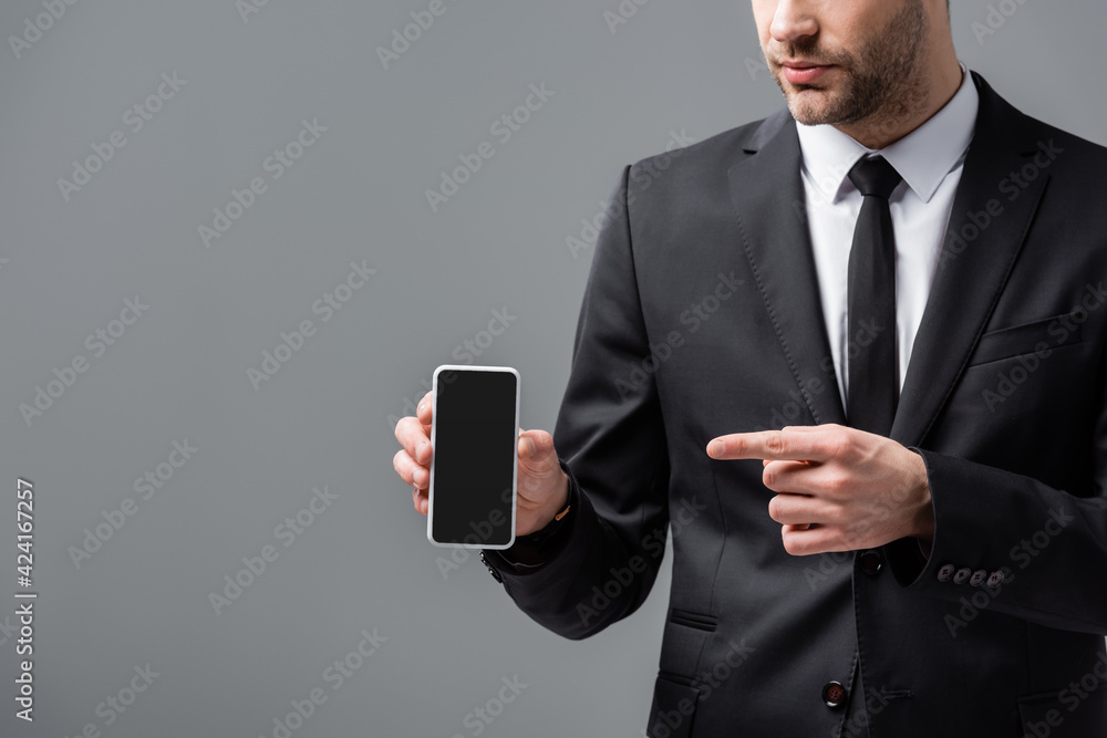 cropped view of businessman in suit pointing at mobile phone with blank screen isolated on grey cropped view of businessman in suit pointing at mobile phone with blank screen isolated on grey