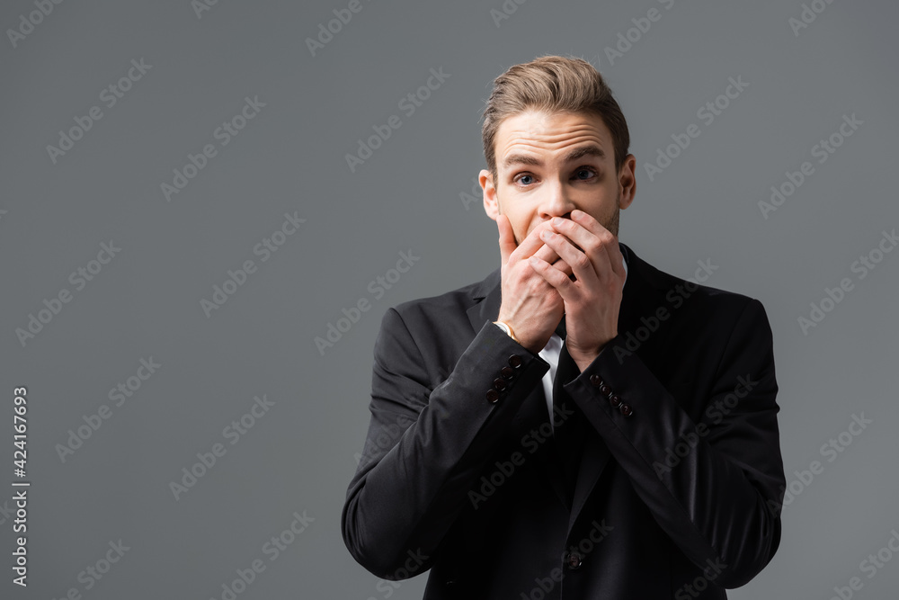 shocked manager looking at camera and covering mouth with hands isolated on grey shocked manager looking at camera and covering mouth with hands isolated on grey
