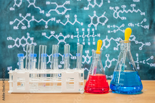 Laboratory glassware with blackboard background with various chemical formulas.