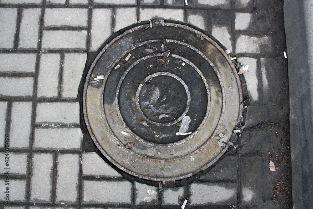 Manhole cover on the road in the asphalt