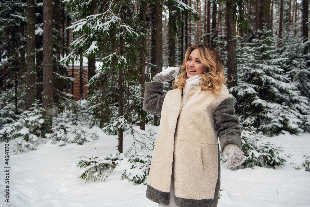 Cute young blonde in a fur coat playing snowballs in the winter in the forest Cute young blonde in a fur coat playing snowballs in the winter in the forest
