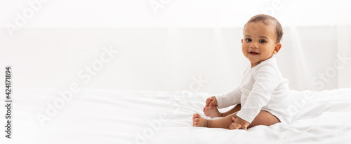 Happy Black Little Baby Girl Sitting In Bedroom At Home