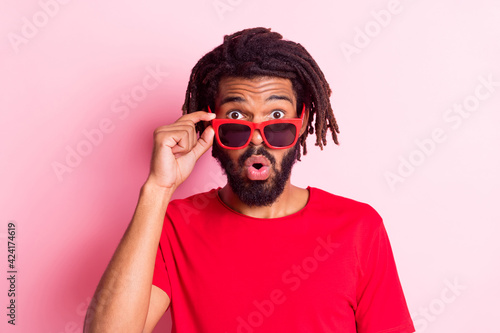 Photo of impressed funky dark skin man dressed red t-shirt arm hand eyeglasses big eyes isolated pink color background
