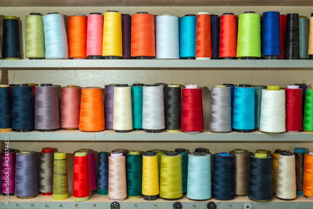 Colorful sewing tread bobbins with lined up on the shelf Colorful sewing tread bobbins with lined up on the shelf