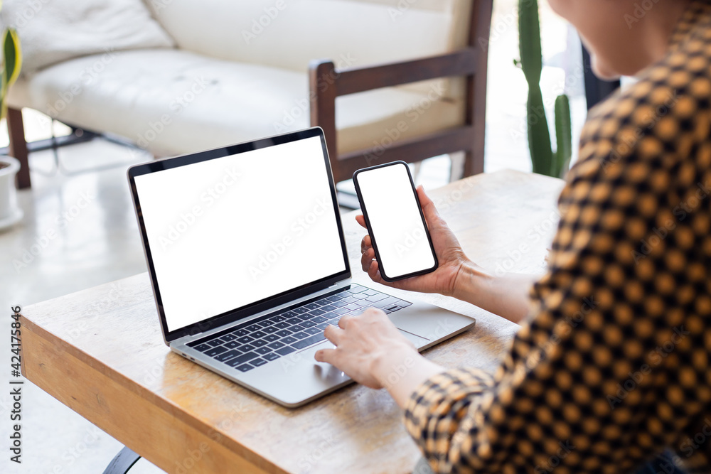 Fototapeta premium computer screen,cell phone blank mockup.hand woman work using laptop texting mobile.white background for advertising,contact business search information on desk in cafe.marketing,design
