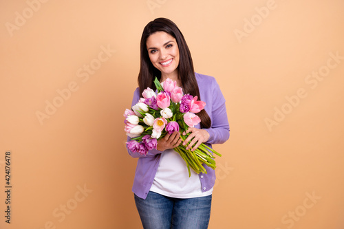 Photo of cheerful woman happy positive smile hold flower bouquet birthday present isolated over beige color background