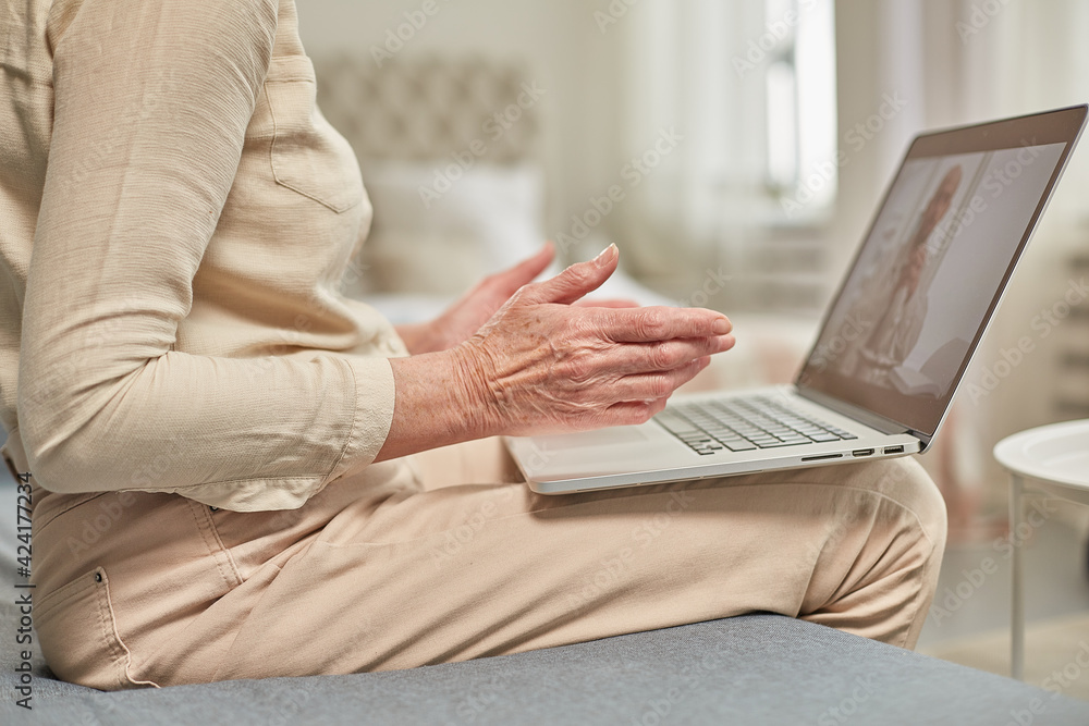 Fototapeta premium An elderly woman communicates remotely via a laptop with her doctor. Telemedicine concept