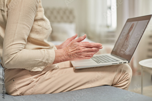 An elderly woman communicates remotely via a laptop with her doctor. Telemedicine concept