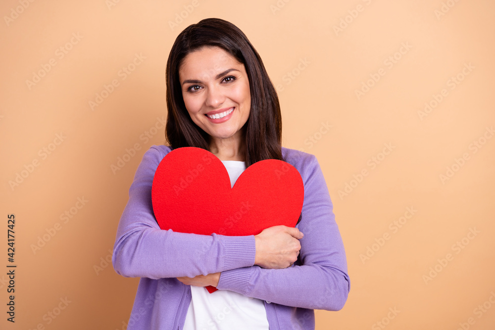 Photo of cheerful woman happy smile hug cuddle big red heart valentine day isolated over beige color background Photo of cheerful woman happy smile hug cuddle big red heart valentine day isolated over beige color background