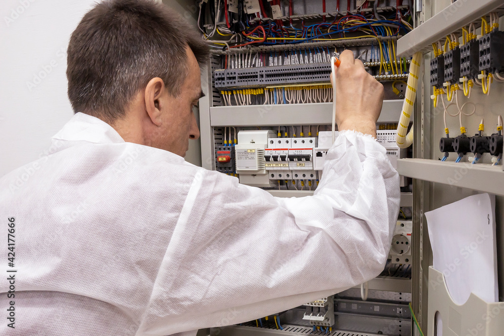 Obraz premium The electrician engineer tests, repairs the electrical control circuitry of the electrical system. Control cable.
