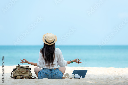 Lifestyle freelance woman relax and sitting meditation on the beach.  Asia people using laptop working for success and together your work pastime and meeting conference on internet in holiday