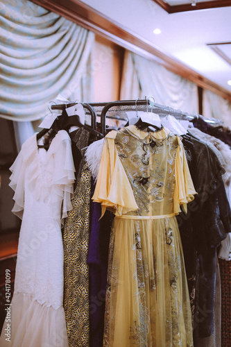 Vintage designer dresses and clothes from different materials and colors hanging in a row