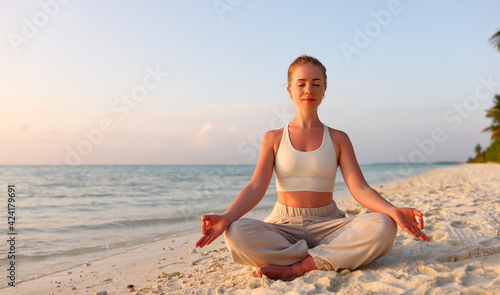 Peaceful woman meditating in Padmasana on coast