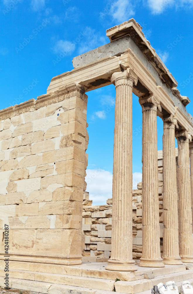 Greece. Athens. Ionian portico of Erechtheion temple on ancient Acropolis (421-406 BC) with a colonnade on the eastern facade against a blue sky with clouds. Travel and excursions to historical sites